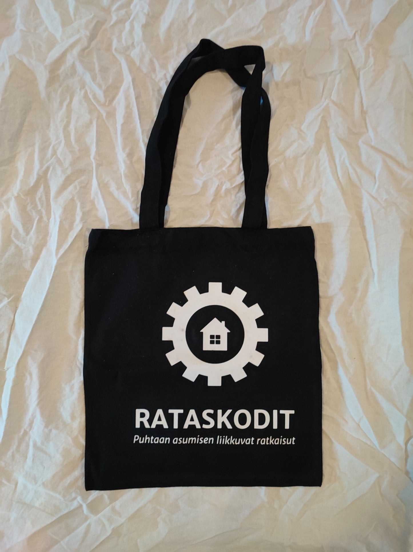 Rataskotien musta kassi valkoisella painetulla logolla.